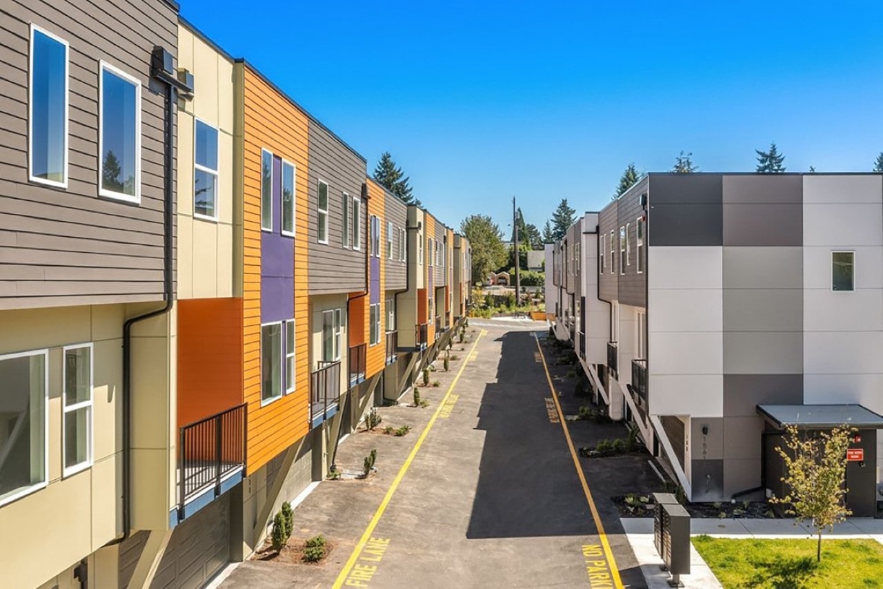 An overhead view of a row of new, colorful townhouses along a paved access road marked as a fire lane.