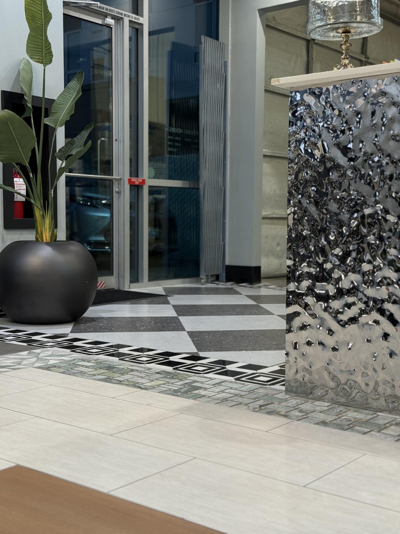 View of the Oscar Surfaces showroom entrance, featuring patterned floor tiles and a textured chrome reception desk.