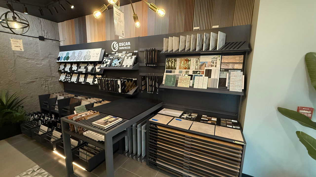  A large display wall in the Oscar Surfaces showroom featuring a wide variety of mosaic and sample tiles under modern light fixtures. Image 2