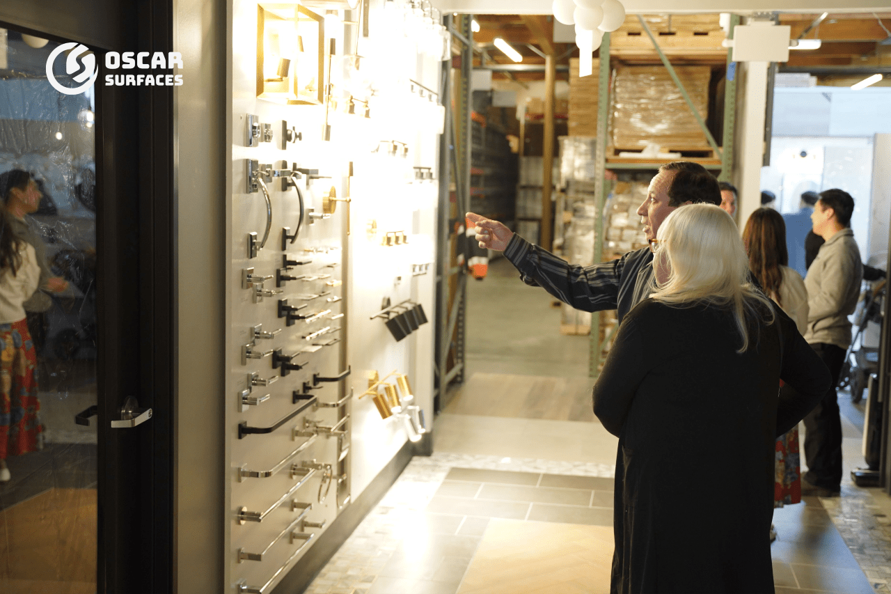  Customers browsing a display wall of chrome and gold bathroom hardware in the Oscar Surfaces showroom.