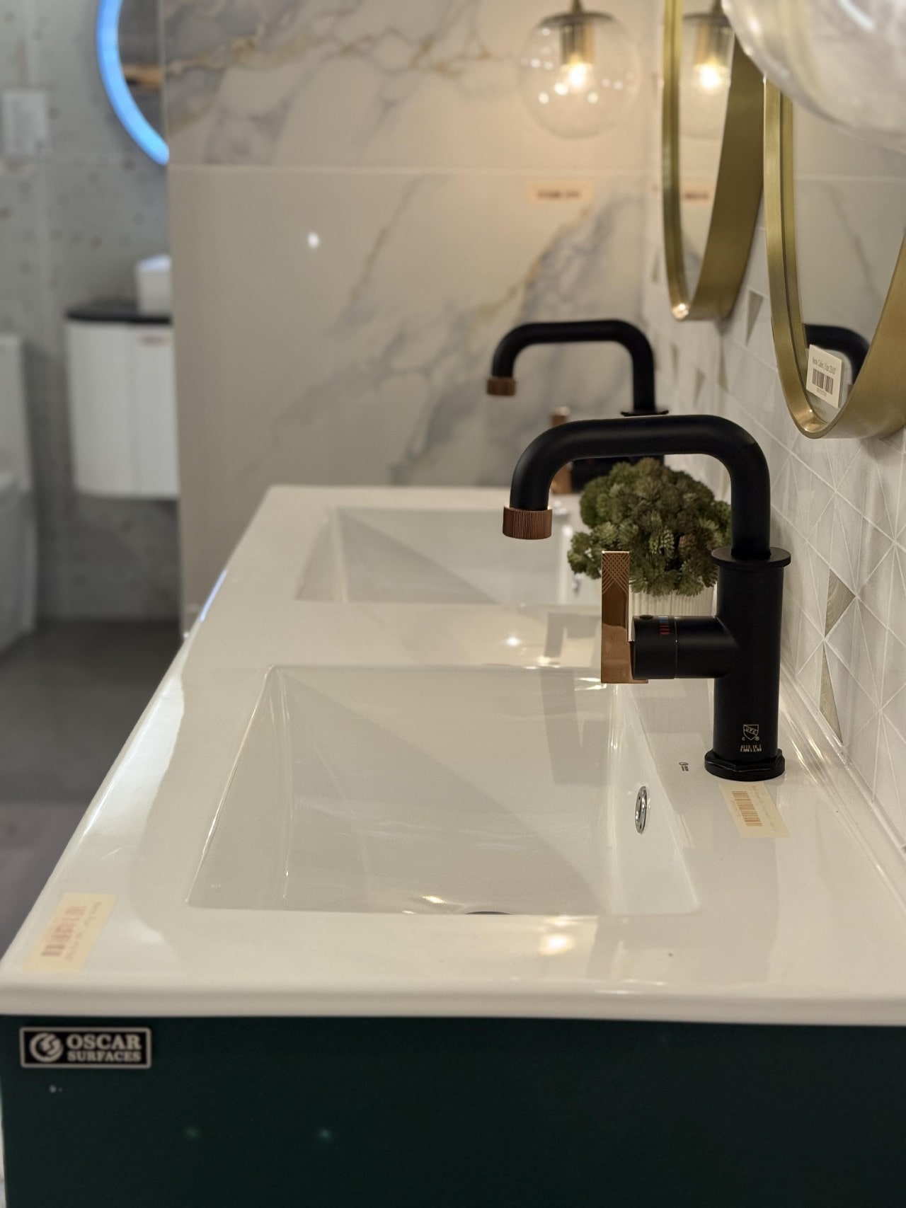 Close-up of a white bathroom vanity with modern matte black and rose gold faucets.