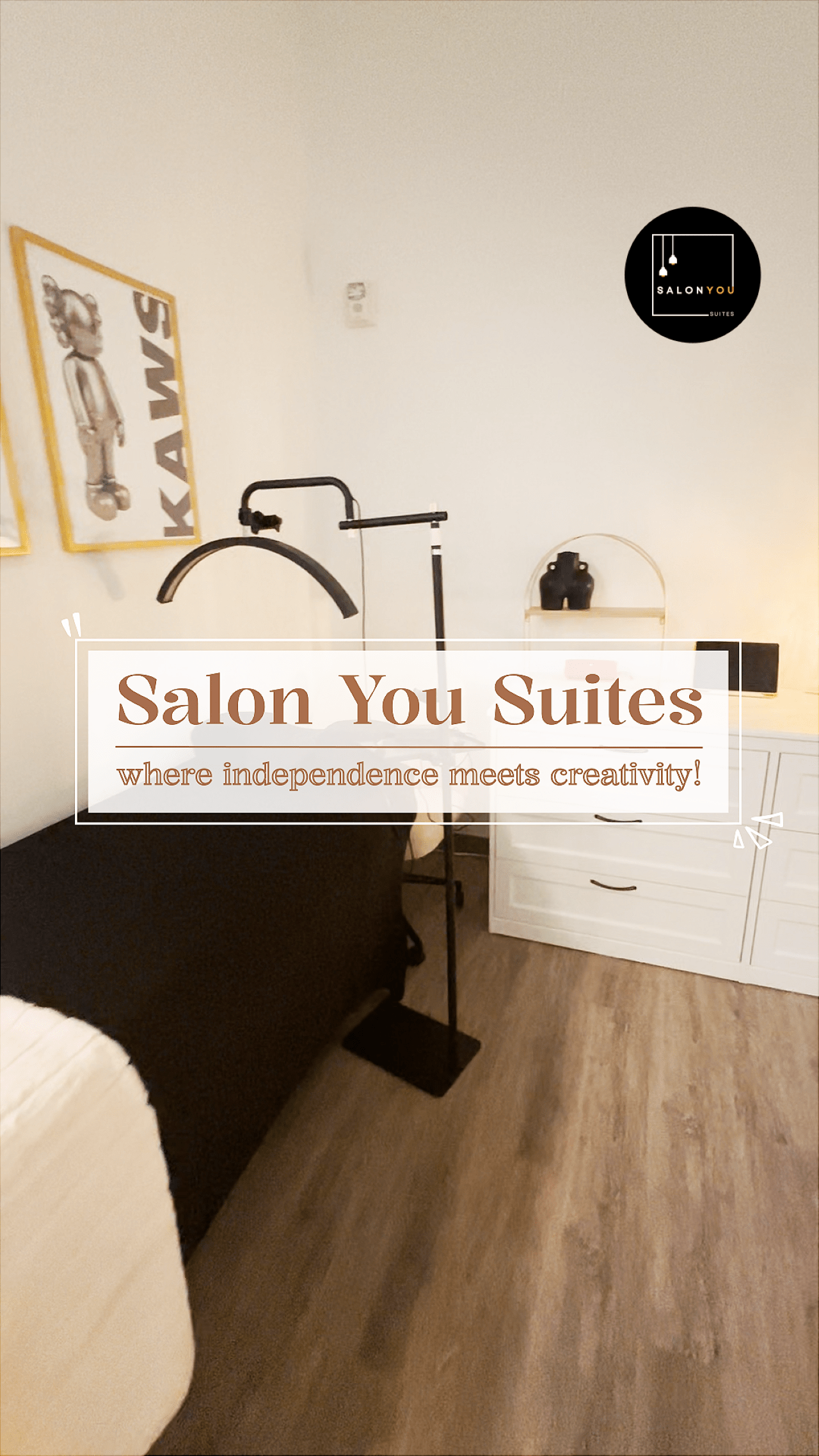 Inside a private Salon You suite with a treatment bed, ring light, and KAWS artwork on the wall, captioned "where independence meets creativity!"